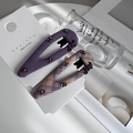 Détail de barrettes en tissu violet avec strass et lettres dorées sur support blanc - Ensemble de Pince Clic-Clac en Tissu Violet