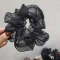Dettaglio di un elastico per capelli in organza nera con trama velata e strati plissettati - Nero Perlato