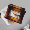 Macro shot of an amber tortoiseshell hair claw clip with geometric hollow square design - Amber