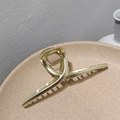 Dettaglio di un fermaglio per capelli in metallo oro chiaro con design incrociato - Oro Opaco