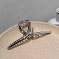 Detail of silver alloy hair claw clip with metallic twist design on a ceramic tray - Silver