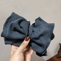 Detailed view of large dark blue ribbed knit bow accessory held in hand showing soft texture - Blue Gray