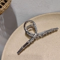 Dettaglio molletta per capelli in metallo argento stile bambù su piatto beige - Argento