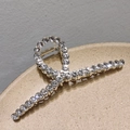 Dettaglio di un grande fermaglio per capelli in metallo dorato con strass e molla a vista - Stile Zirconia