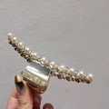 Détail de la pince à cheveux en alliage doré avec perles et strass tenue à la main - Perle et Petit Strass