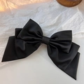 Dettaglio di un grande fiocco per capelli in raso nero con texture setosa - Fiocco a tre strati