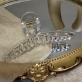 Close-up of a clear hair claw clip with golden spring on a vintage mirror surface - Clear White