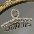 Dettaglio macro del fermaglio per capelli dorato con perle bianche eleganti su specchio - Stile Incrociato