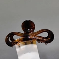 Détail d'une pince à cheveux en résine ambrée avec un mécanisme à ressort métallique fort - Ambre