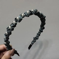 Dettaglio di un cerchietto in raso grigio scuro con tessuto a pieghe e perle bianche - Verde