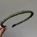 Detailed view of the dark green pleated leather headband showing texture and fabric tips - Green
