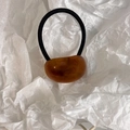 Close-up of a minimalist amber resin oval bead on a black elastic hair tie for women - Amber