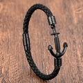 Pulsera de hombre en cuero trenzado negro con cierre de ancla negra sobre fondo de madera - Capa Única / Negro de Una Capa (Ancla Negra)
