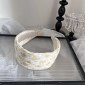 Close-up of a wide floral headband with yellow blossoms on a glass tray - Yellow