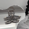 Dettaglio molletta per capelli grigia con perle e cristallo su superficie a specchio - Grigio