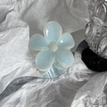 Primer plano de una pinza para el pelo de flor azul claro sobre una superficie de espejo - Azul claro