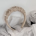Detailed view of beige pleated satin headband with a handmade label and soft texture - Beige