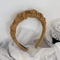 Detail of a handmade pleated yellow satin headband with premium textured fabric finish - Turmeric