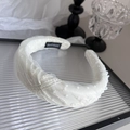 Détail du serre-tête en dentelle crème avec étiquette fait main sur plateau en verre - Beige