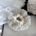 Detail van champagne satijnen scrunchie met gelaagde witte tule en zwarte stippen - Beige