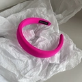 Detail eines neonpinken Schwammstirnbands mit handgefertigtem Etikett auf Seidenpapier - Rosenrot