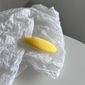 Detail of a bright yellow oval hair clip with textured fabric on wrinkled paper background - Yellow