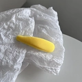 Detail of yellow fabric-wrapped teardrop hair clip with fine ribbed texture on paper - Yellow