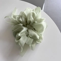 Detailed texture of light green organza scrunchie with long ribbons and silky finish - Green
