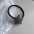 Detalle del dije de estrella gris con texto France Handmade en una goma de pelo negra - Gris