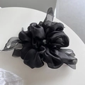Detailed close-up of a black silk scrunchie with long ribbons and pleated texture - Black