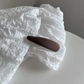 Détail macro d'une pince à cheveux texturée marron chocolat sur papier froissé - Café Clair