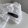 Gros plan sur une pince à cheveux BB en tissu mat noir sur fond de papier blanc texturé - Gris foncé