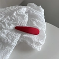 Détail d'une pince à cheveux rouge en tissu sergé sur un fond blanc texturé élégant - Rouge