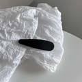 Détail d'une pince à cheveux noire mate minimaliste sur papier blanc texturé élégant - Noir