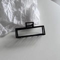 Detalle de una pinza de pelo rectangular grande en negro mate con un fuerte muelle metálico - Negro