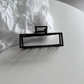 Vista detallada de una elegante pinza para el cabello rectangular negra con diseño hueco - Marrón