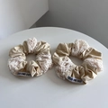 Detailopname van beige katoenen scrunchie met wit kantborduurwerk en merklabel - Combinatieset / Lichtcrème