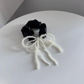 Detail van zwarte satijnen scrunchie met elegante parelmoer strik en kwastjes - Zwart
