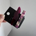 Close-up of marble acetate and wavy hair clips with a gold bow and pearl detail - Dark Purple