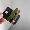 Dettaglio di fermaglio ondulato in acrilico verde oliva e fermaglio marmorizzato con fiocco - Verde