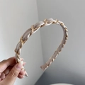 Détail du serre-tête en satin champagne tressé avec une chaîne dorée élégante - Beige