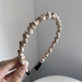 Detalle de diadema de cuero plisado beige con cadena dorada y pedrería de color gris oscuro - Blanco Roto