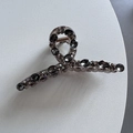 Detailed close-up of luxury shark hair clip with smoky grey crystals and metal spring - Gray