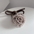 Detail van handgemaakte mesh bloem haarelastiek met een bruine strik en rijke textuur - Beige