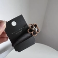 Dettaglio di una molletta per capelli a fiore in velluto marrone con perle metalliche nere - Cachi
