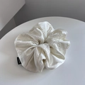 Detail of white satin scrunchie featuring camellia embroidery and Hand Made label - Off White