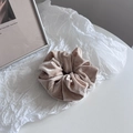 Detail of velvet scrunchie in beige with sparkling silver rhinestones on white surface - Beige