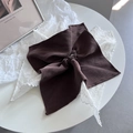 Détail d'un chouchou en dentelle marron foncé avec une texture tricotée sur une table - Marron