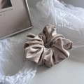 Detail view of champagne velvet scrunchie with soft sheen and pleated texture - Beige