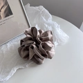 Close-up of champagne satin scrunchie with silk texture and elegant pleated design - Khaki